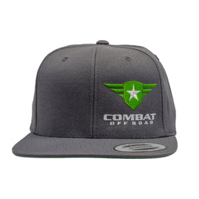 A gray snapback hat featuring the Combat Off Road logo embroidered on the front. The logo includes a green shield with a white star and winged accents, with the words "Combat Off Road" in bold white lettering below. The hat has a flat brim with a sticker on the front indicating its adjustable fit.