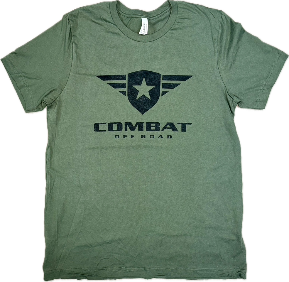 A green t-shirt featuring the Combat Off Road logo printed in black on the chest. The logo includes a shield with a star and winged accents, with the words "Combat Off Road" in bold black letters underneath. The shirt has a crewneck design and short sleeves, offering a comfortable and casual style.